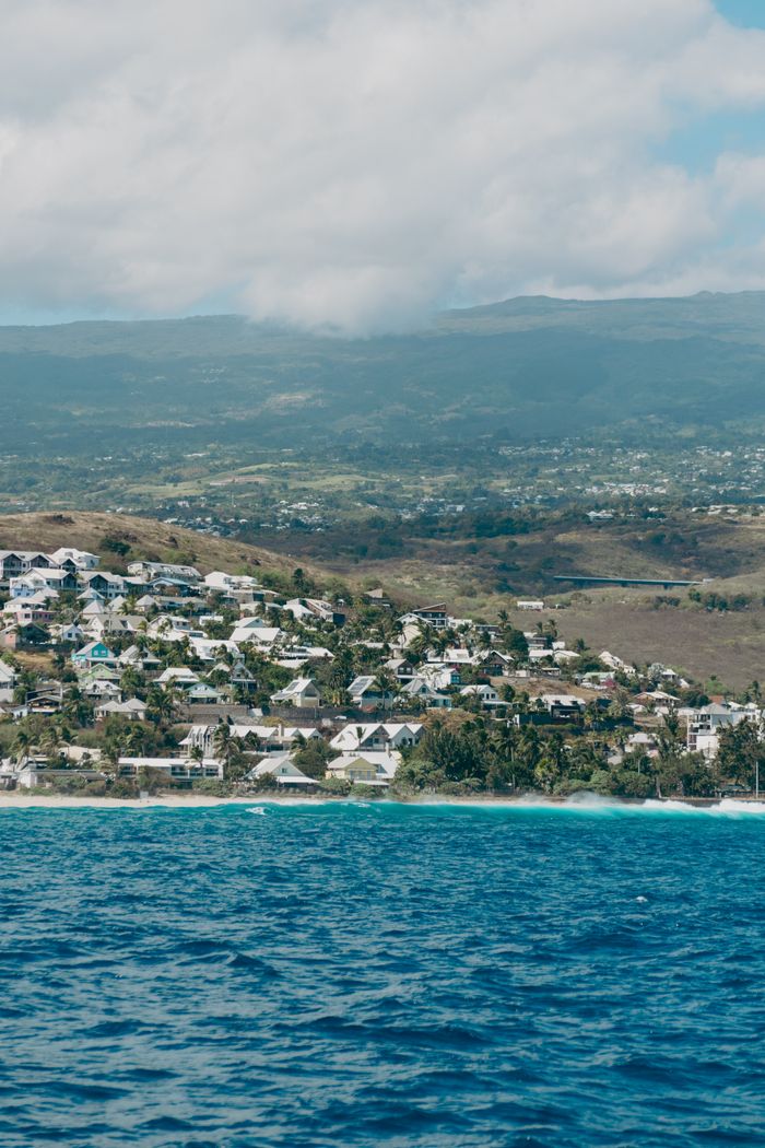 A picturesque coastal view of La Réunion with blue ocean waters and distant mountains.