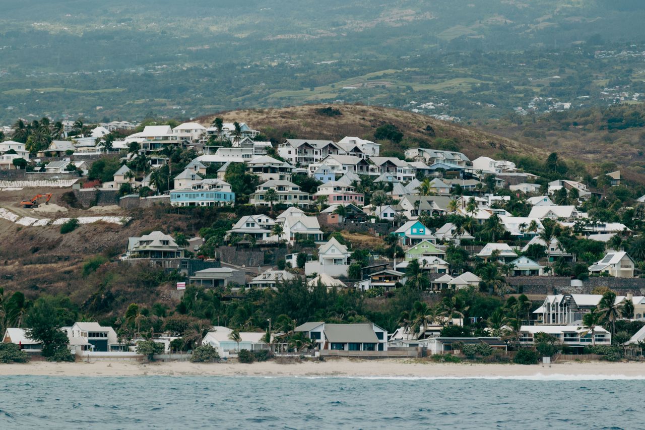 A picturesque coastal town on La Réunion Island, showcasing hillside homes near the ocean.